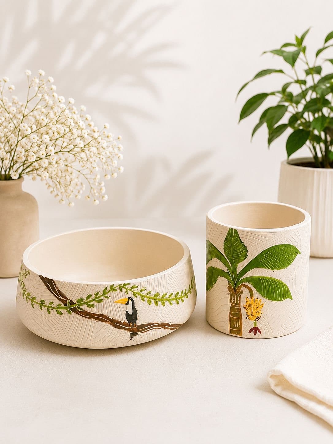 Bowl painted with a toucan on a branch beside a banana palm pot