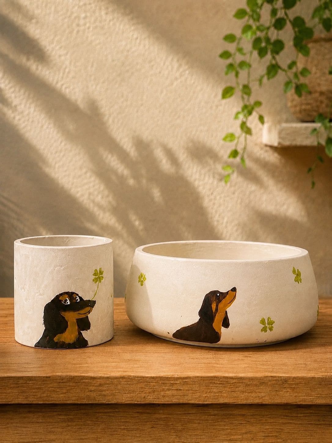 Planter set hand-painted with a black and tan dachshund reaching for a clover, on a wooden shelf