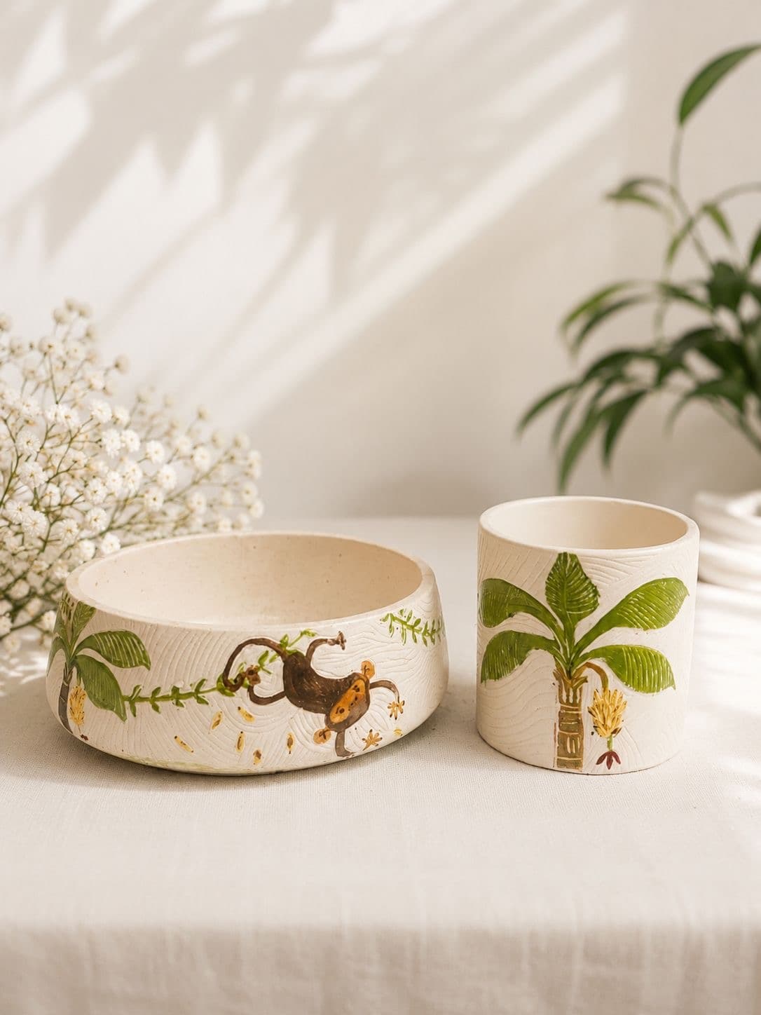 Close-up of a hand-painted monkey swinging along a vine on the side of a carved bowl planter